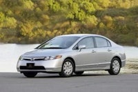 a silver honda civic is parked in front of a lake